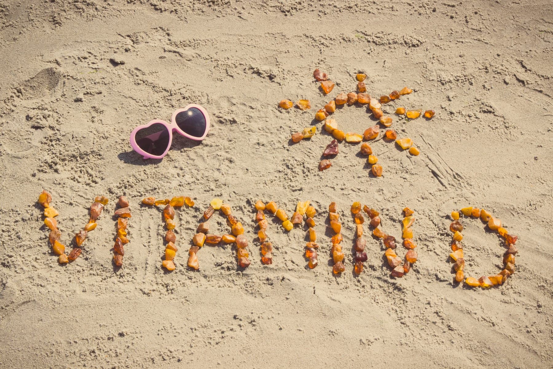 Schriftzug „Vitamin D" aus Steinen im Sand